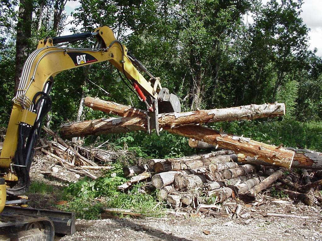 HT830 mini hydraulic thumb, installed on a CAT excavator, picking up two logs.