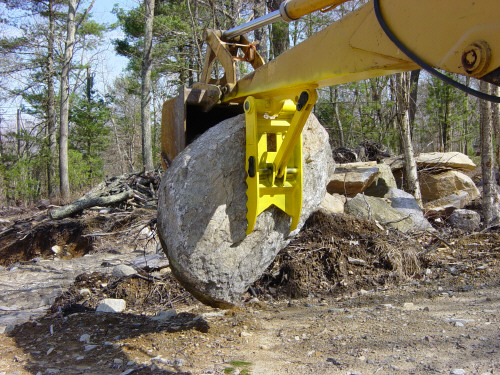 MT1230 excavator thumb, installed on an excavator, lifting a heavy stone.