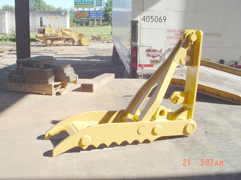 Yellow MT1240 excavator backhoe thumb waiting to be installed on a machine.