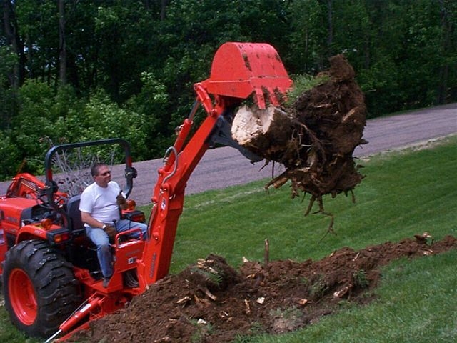Kubota bh90 backhoe lifts a stump out of the ground with MT618, 6"x18" mini thumb from USA Attachments