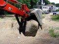 MT824 mini excavator thumb by USA Attachments holding a stone. Great for grasping and moving objects.