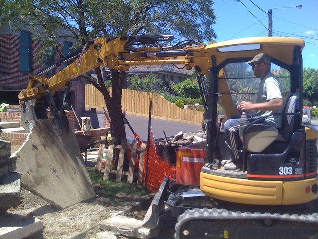 CAT 303 SR mini excavator picks up a large slab of concrete with 8