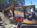 CAT 303 SR mini excavator picks up a large slab of concrete with 8"x30" thumb