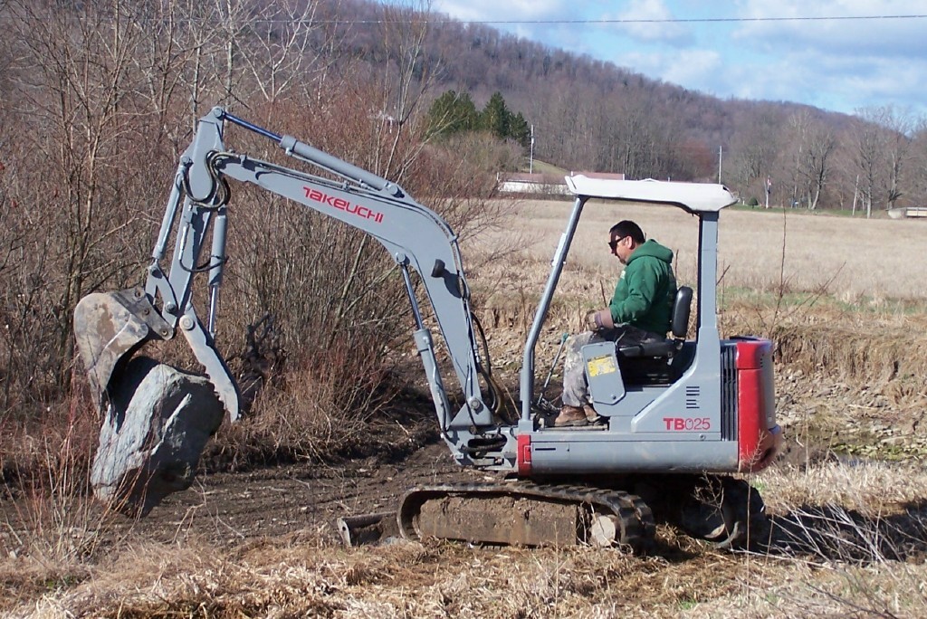 Takeuchi tb025 mini excavator with thumb picks up a big rock