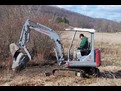 takeuchi tb025 mini excavator with thumb picks up a big rock