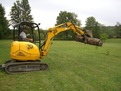 USA Attachments presents the HT830 mini excavator hydraulic thumb on a JCB mini excavator picking up a log.