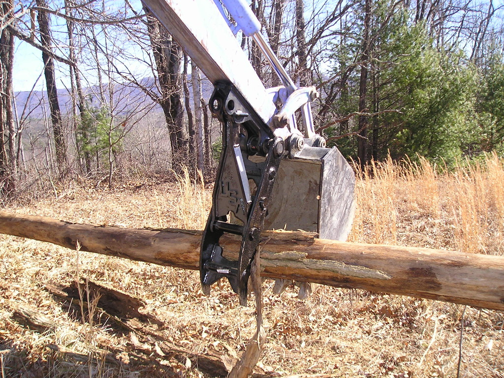 MT1035 excavator thumb picking up a log