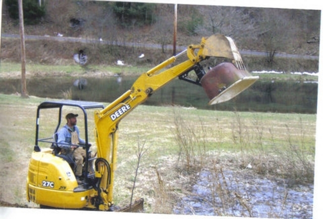 DEERE 27C excavator with a MT1240 excavator thumb, picking up an old tub.
