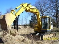 MT1240 excavator thumb installed on a Komatsu PC75UU picking up a large stone