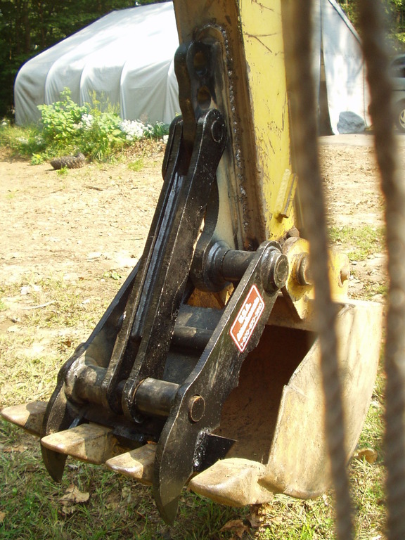 MT618 thumb installed with a tight fit, showing the thumb fingers between the bucket teeth. This is a terramite t5c compact loader backhoe.