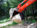 MT824 mini excavator thumb picking up stone, installed on a Kubota excavator