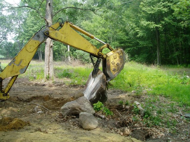 MT830 mini thumb welded on a backhone, picking up a large stone.