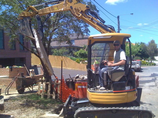 CAT 303 SR with mini excavator thumb lifts concrete slab in Australia