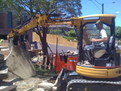 CAT 303 SR mini excavator picks up a large slab of concrete with 8"x30" thumb